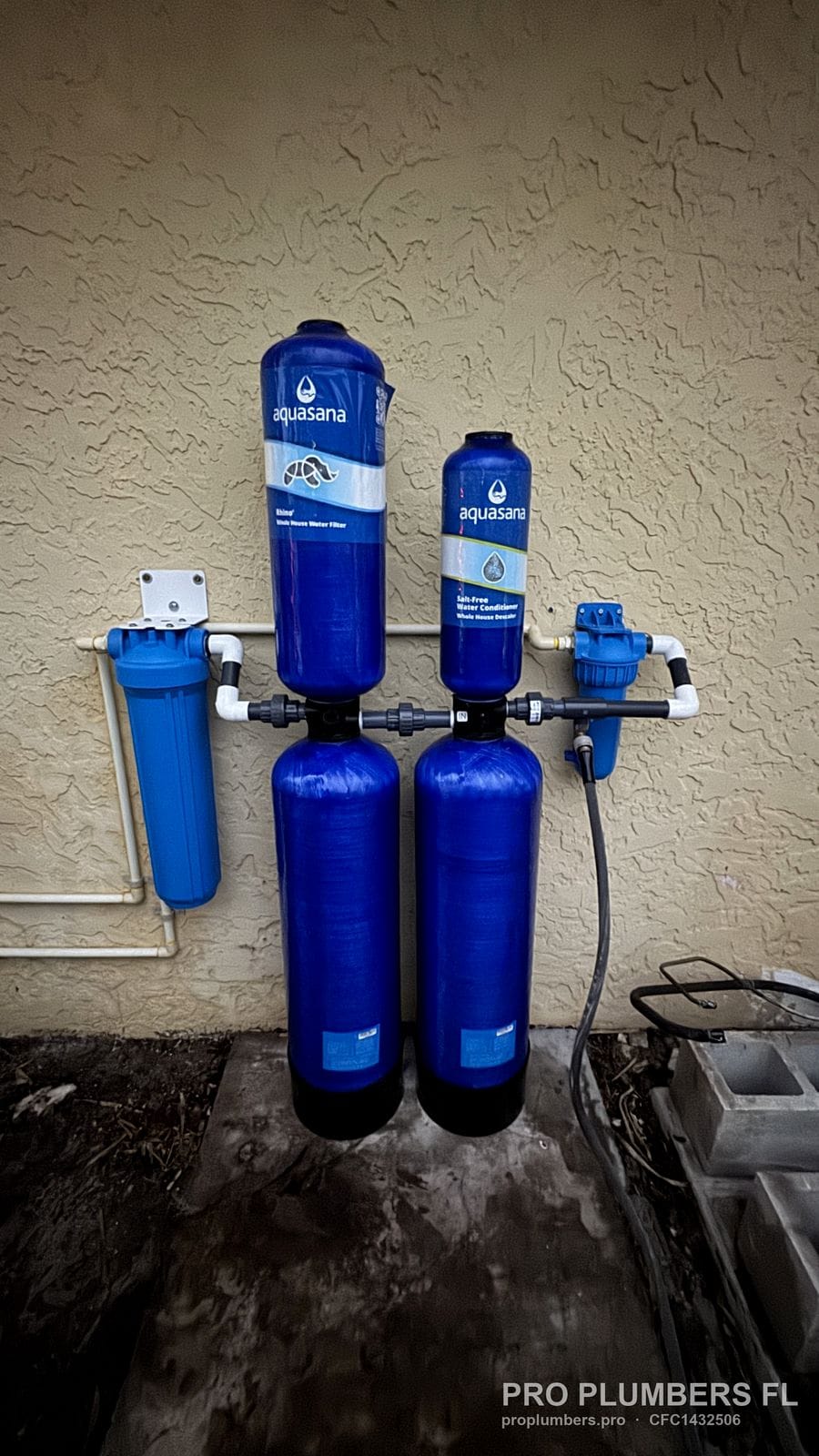 Aquasana two-tank whole-house filtration system with pre- and post-filter housings on an exterior wall in Tierra Verde, Florida by PRO PLUMBERS FL, LLC (licence CFC1432506)