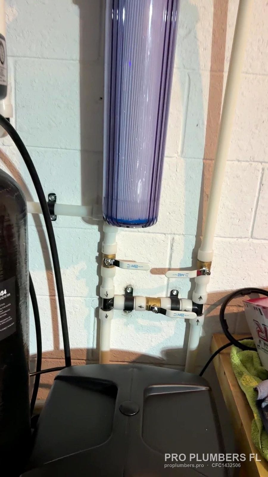 Clear whole-house filter housing with PVC bypass valves on a block wall in Bradenton, Florida by PRO PLUMBERS FL, LLC (licence CFC1432506)