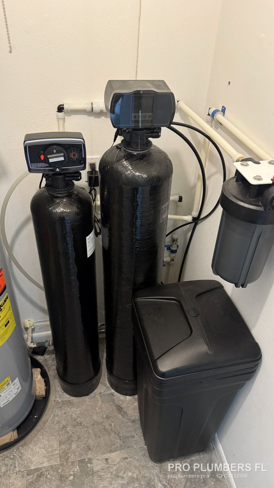 Filter tank, water softener and prefilter installed in a closet beside the water heater in Belleair, Florida by PRO PLUMBERS FL, LLC (licence CFC1432506)