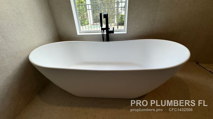 Double-slipper freestanding tub with matte black floor-mounted filler under a window in Westchase, Florida by PRO PLUMBERS FL, LLC (licence CFC1432506)