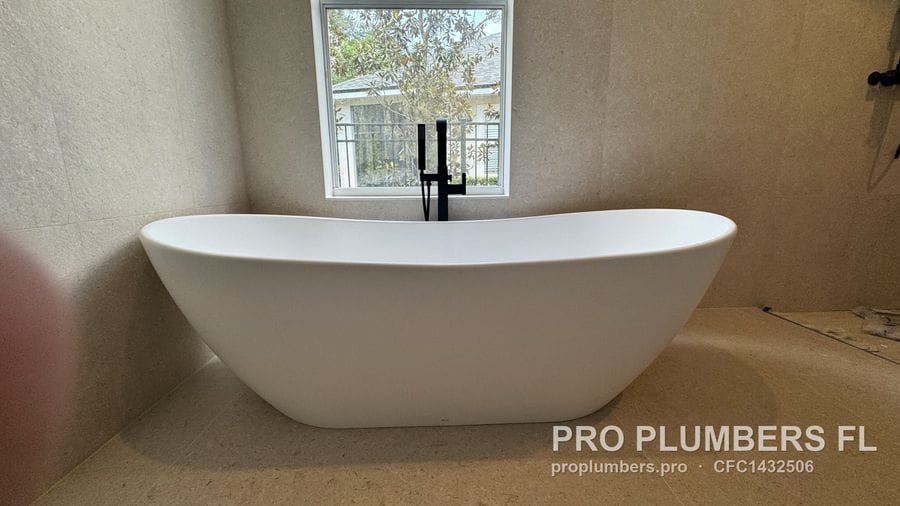 Double-slipper freestanding tub in front of a window with floor-mounted filler in Westchase, Florida by PRO PLUMBERS FL, LLC (licence CFC1432506)