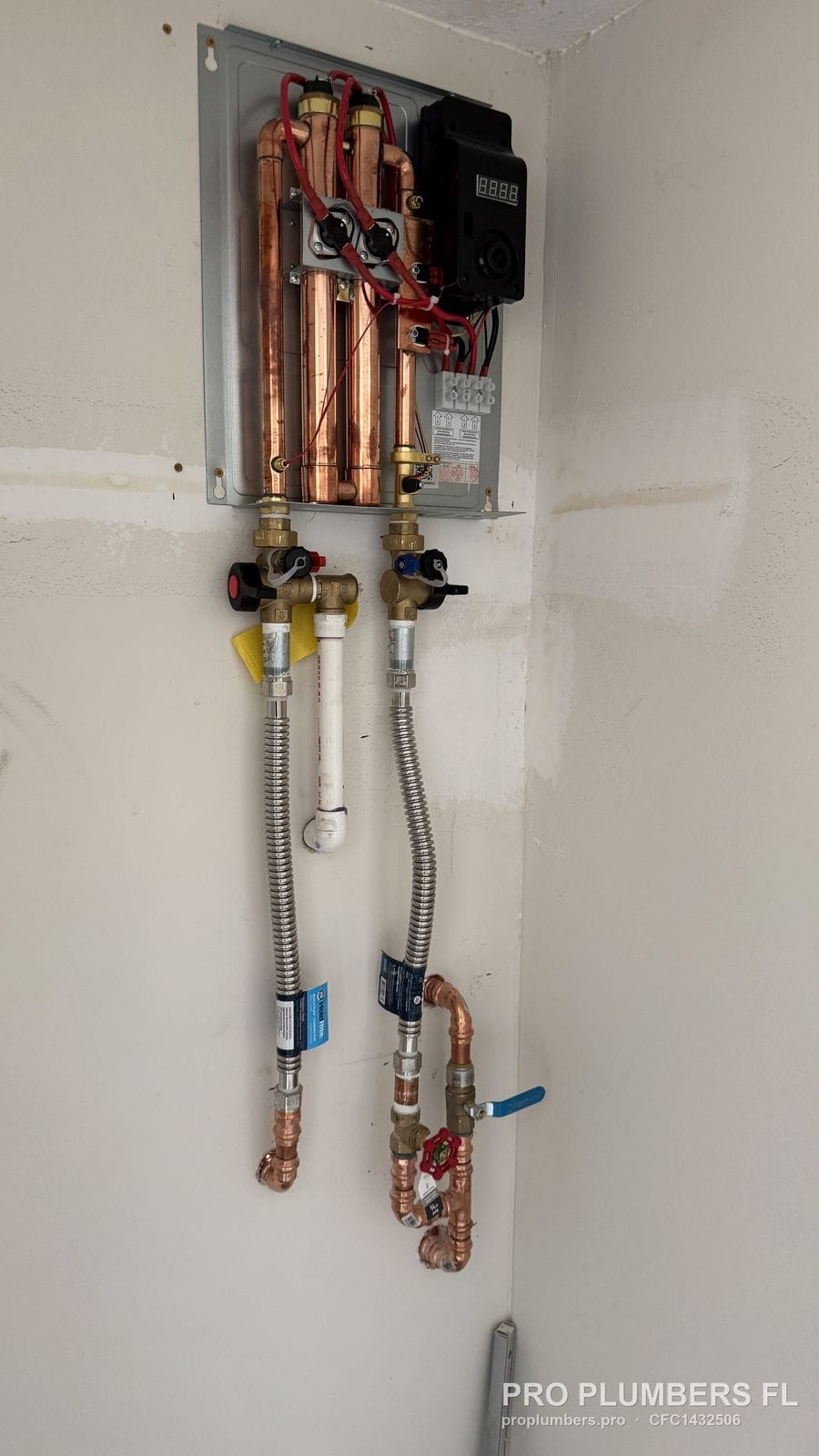 Electric tankless water heater with cover removed showing copper heating chambers and isolation valves in Sarasota, Florida by PRO PLUMBERS FL, LLC (licence CFC1432506)