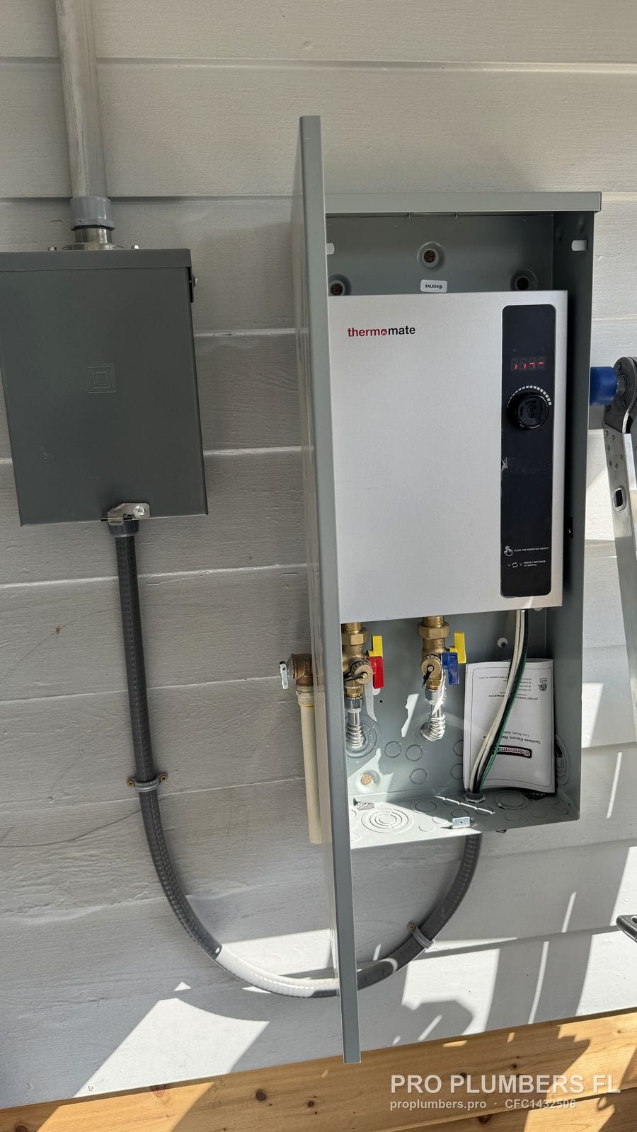 Electric tankless water heater in an open metal outdoor enclosure next to a disconnect in Treasure Island, Florida by PRO PLUMBERS FL, LLC (licence CFC1432506)