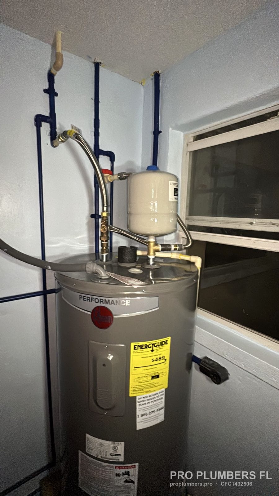 Electric tank water heater with expansion tank and PEX lines beside a window in St. Pete Beach, Florida by PRO PLUMBERS FL, LLC (licence CFC1432506)
