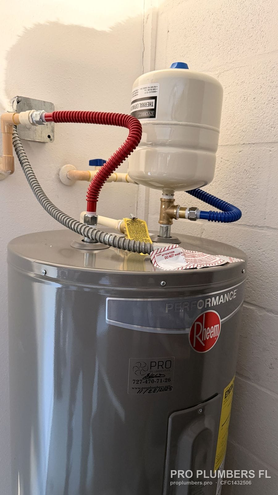 Electric tank water heater with thermal expansion tank and red and blue flexible connectors in Wesley Chapel, Florida by PRO PLUMBERS FL, LLC (licence CFC1432506)