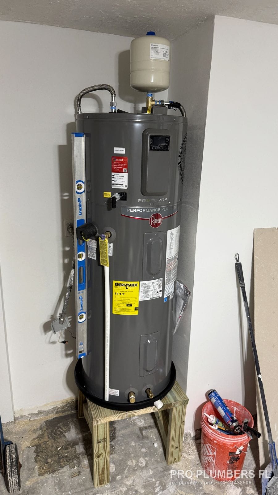 Electric tank water heater on a raised wooden stand with drain pan and thermal expansion tank in Belleair Beach, Florida by PRO PLUMBERS FL, LLC (licence CFC1432506)