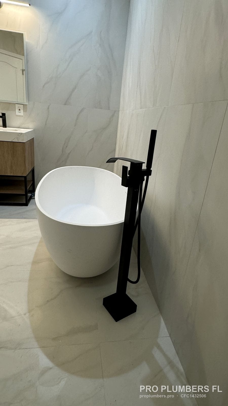 Freestanding tub and floor-mounted filler in a remodeled bathroom with floating vanity in Venice, Florida by PRO PLUMBERS FL, LLC (licence CFC1432506)