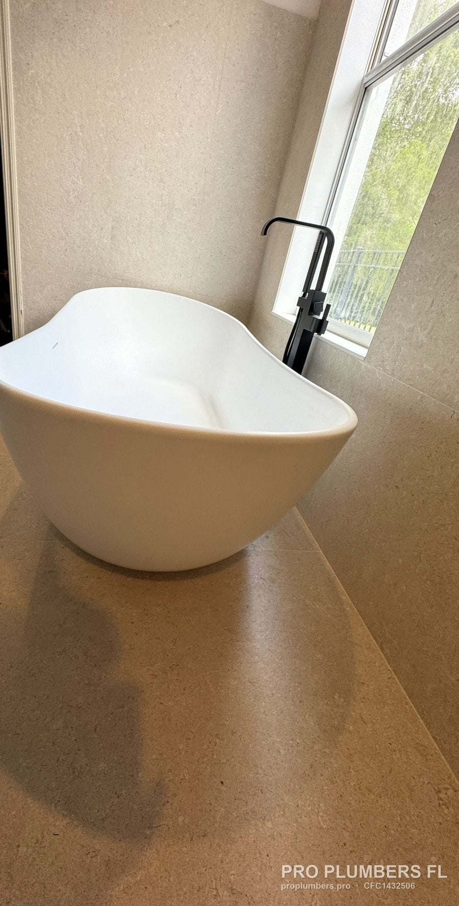 Freestanding tub and matte black floor-mounted filler beside a window in Westchase, Florida by PRO PLUMBERS FL, LLC (licence CFC1432506)