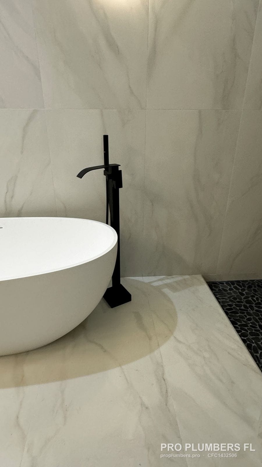 Freestanding tub edge and matte black floor-mounted filler on marble-look tile in Venice, Florida by PRO PLUMBERS FL, LLC (licence CFC1432506)