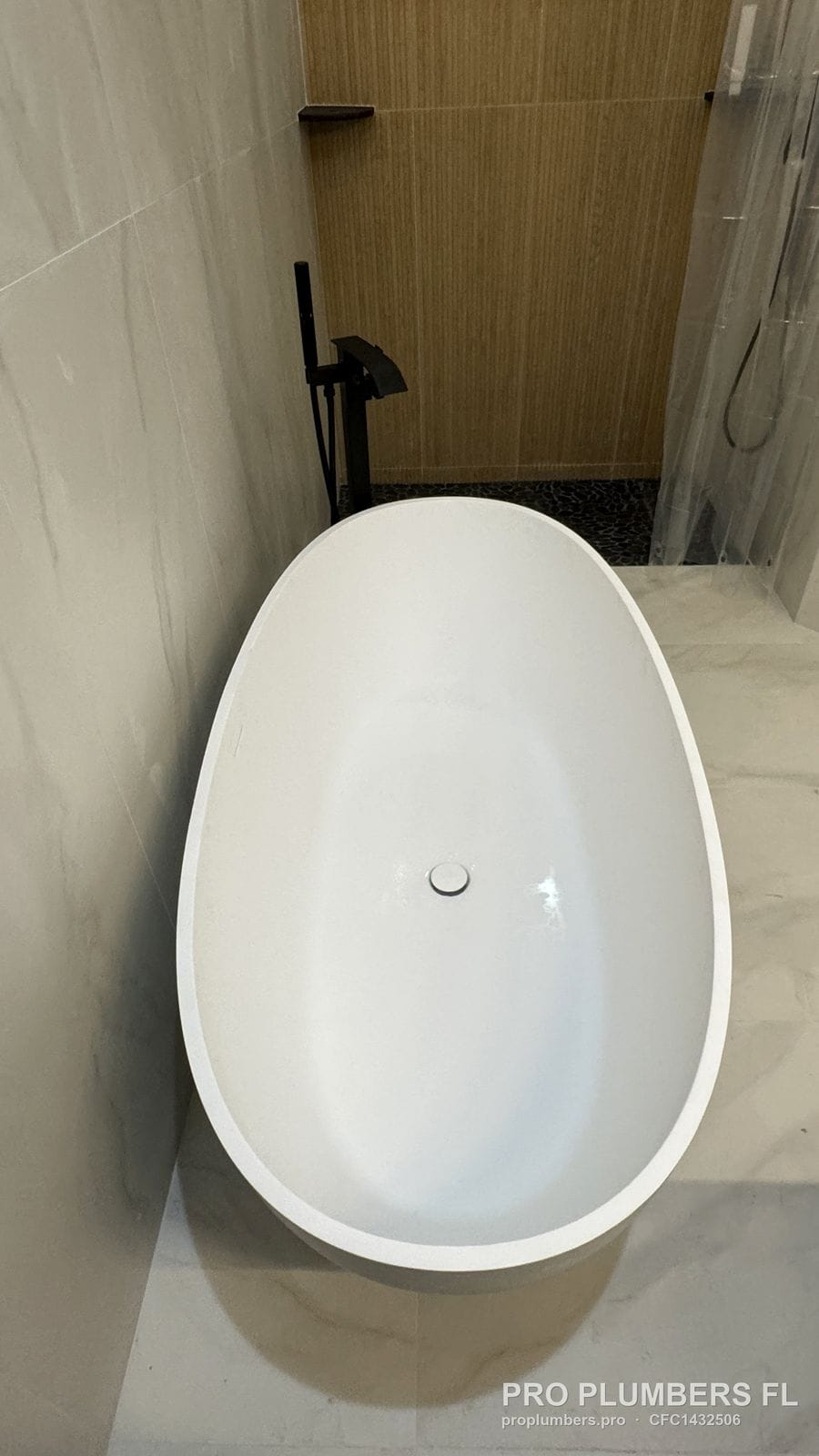 Overhead view of an oval freestanding tub beside a walk-in shower with pebble floor in Venice, Florida by PRO PLUMBERS FL, LLC (licence CFC1432506)