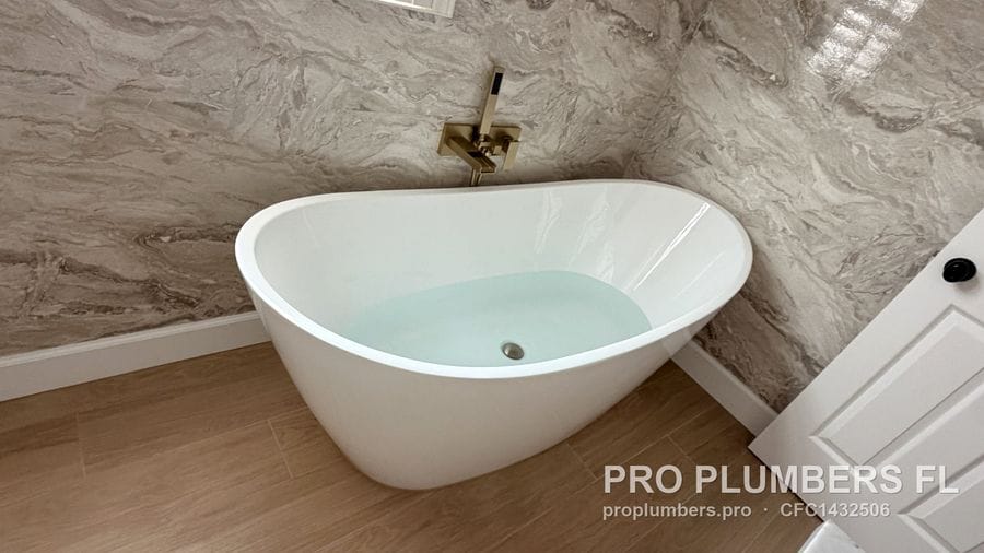 Freestanding tub filled for a water test with brushed gold wall-mounted filler in Clearwater, Florida by PRO PLUMBERS FL, LLC (licence CFC1432506)