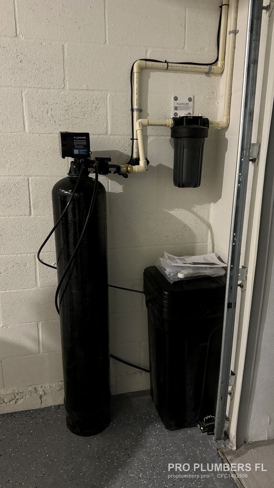Water softener, brine tank and wall-mounted prefilter installed in a garage corner with CPVC bypass piping in Wesley Chapel, Florida by PRO PLUMBERS FL, LLC (licence CFC1432506)