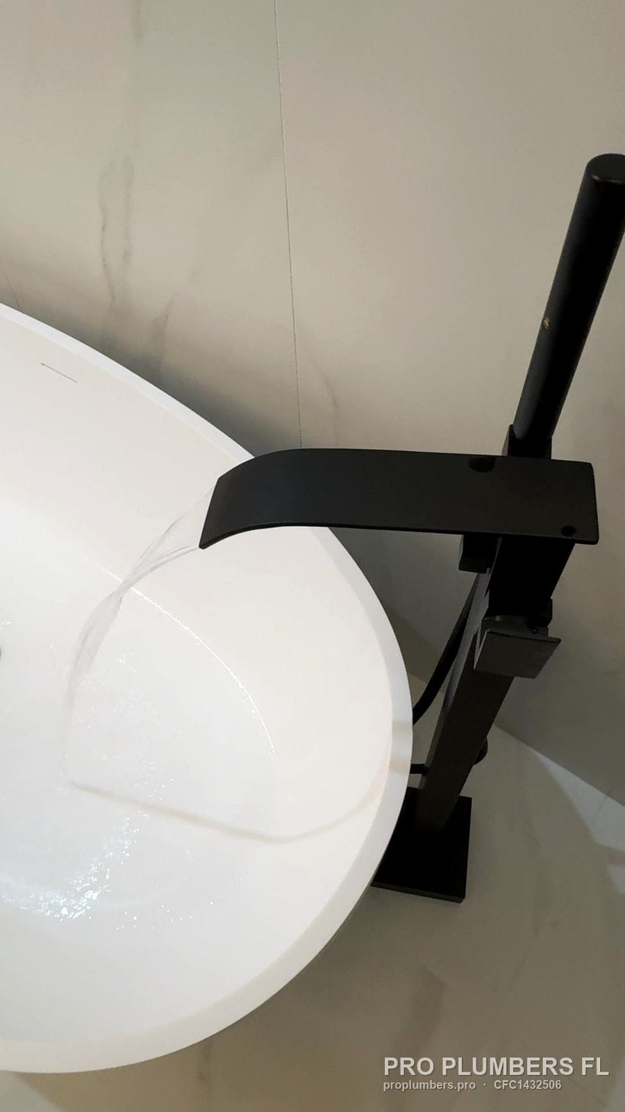 Matte black floor-mounted tub filler spout over an oval freestanding tub in Venice, Florida by PRO PLUMBERS FL, LLC (licence CFC1432506)
