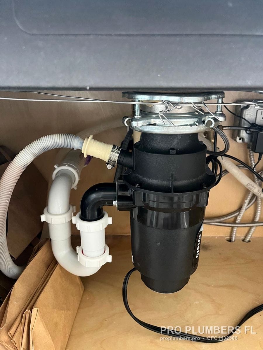Moen GXP50C disposal with PVC trap and dishwasher drain hose under a sink in Clearwater, Florida by PRO PLUMBERS FL, LLC (licence CFC1432506)