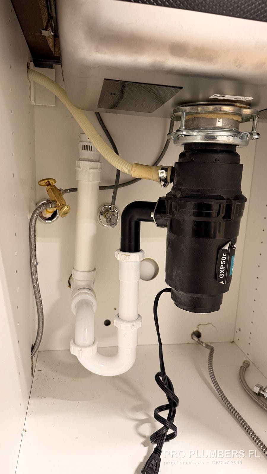 Moen GXP50C disposal with PVC trap and supply valves inside a sink cabinet in Largo, Florida by PRO PLUMBERS FL, LLC (licence CFC1432506)
