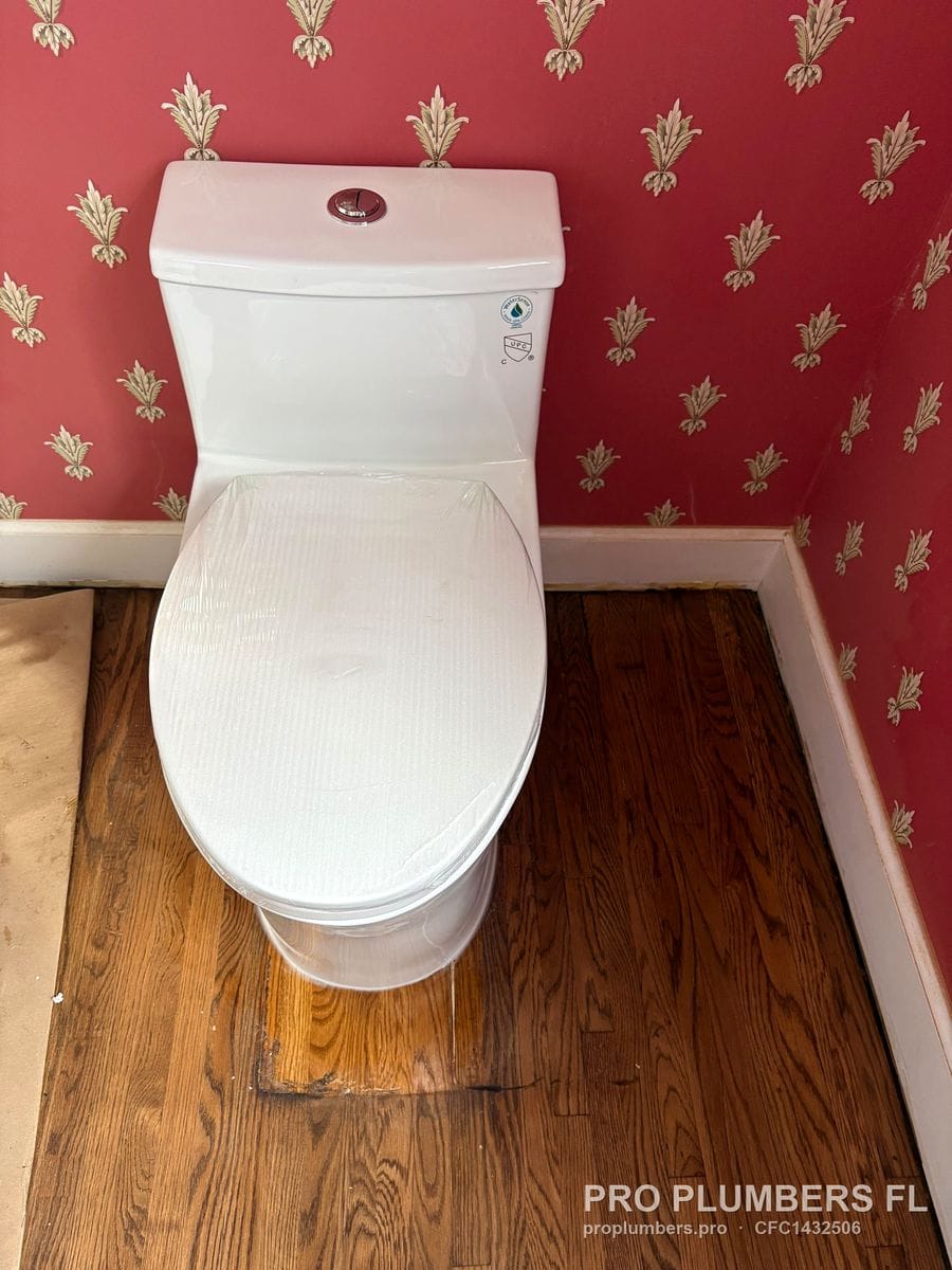 One-piece dual-flush toilet with protective film on the seat on a hardwood floor in Clearwater, Florida by PRO PLUMBERS FL, LLC (licence CFC1432506)