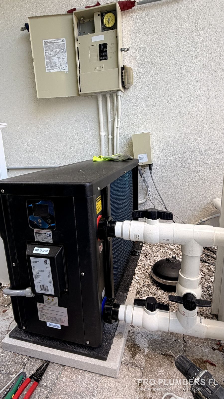 Pool heat pump set on a pad beside the pool equipment panel with new PVC piping in Palm Harbor, Florida by PRO PLUMBERS FL, LLC (licence CFC1432506)