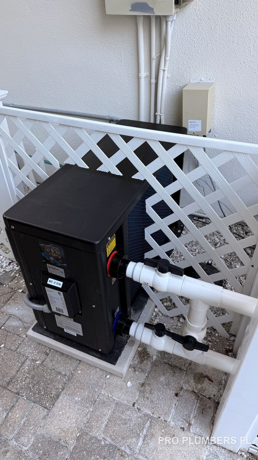 Finished pool heat pump behind white lattice with PVC valves and bypass in Palm Harbor, Florida by PRO PLUMBERS FL, LLC (licence CFC1432506)