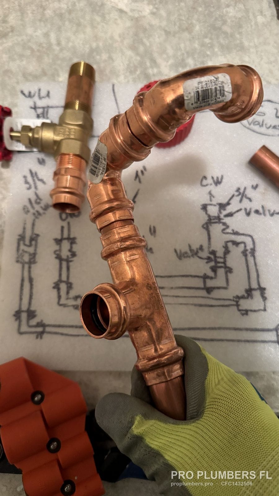 Press-fit copper elbow tee and coupling assembly held in hand in Sarasota, Florida by PRO PLUMBERS FL, LLC (licence CFC1432506)
