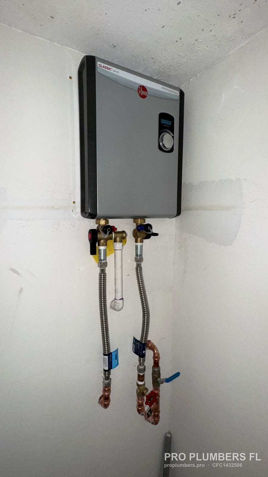 Rheem electric tankless water heater with isolation valves on an interior wall in Sarasota, Florida by PRO PLUMBERS FL, LLC (licence CFC1432506)