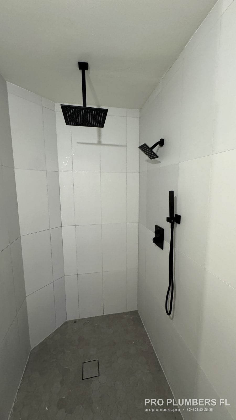 Matte black ceiling rain head, wall shower and handheld in a curbless shower in Dunedin, Florida by PRO PLUMBERS FL, LLC (licence CFC1432506)