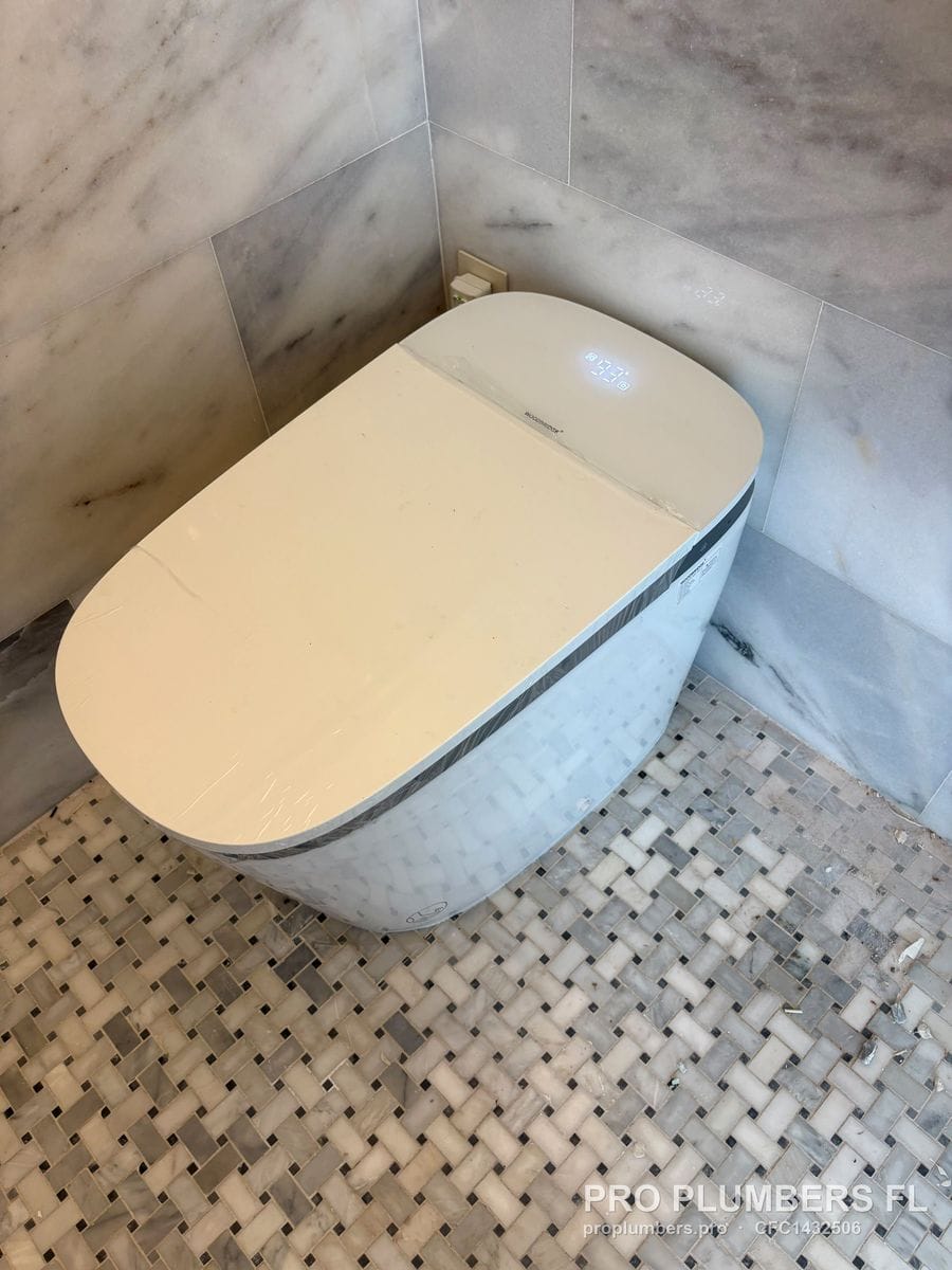 Smart toilet in protective film on basketweave marble mosaic floor with marble walls in Clearwater, Florida by PRO PLUMBERS FL, LLC (licence CFC1432506)
