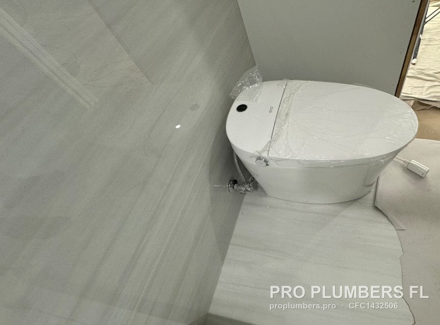 New smart toilet still in protective film set on a finished tile floor with floor protection paper in Largo, Florida by PRO PLUMBERS FL, LLC (licence CFC1432506)