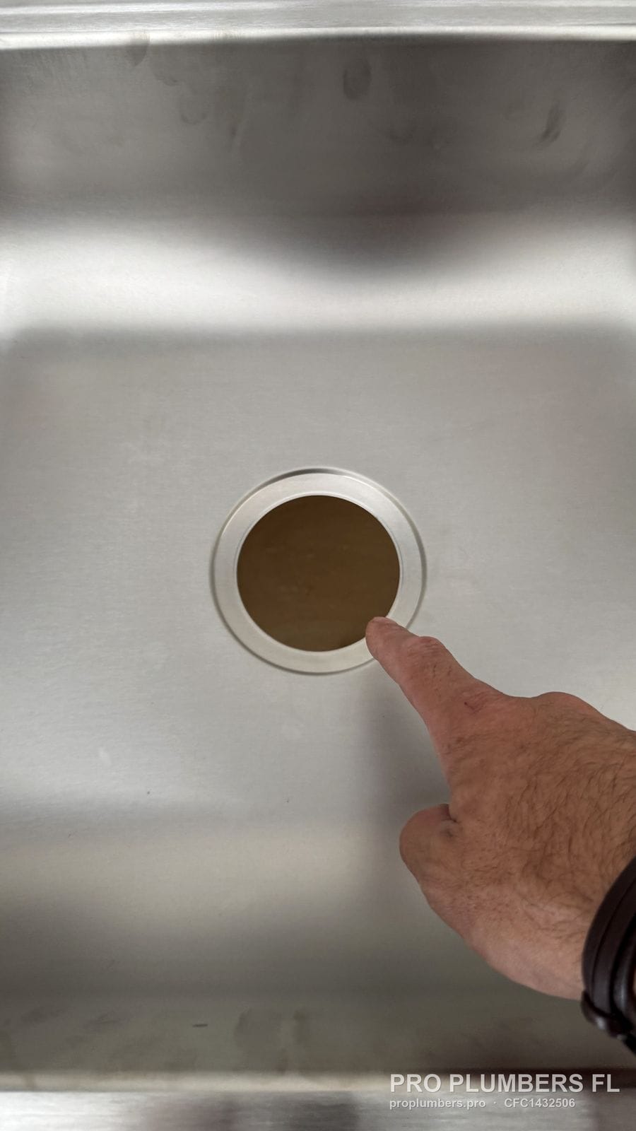 Stainless steel sink drain opening being pointed out in Clearwater, Florida by PRO PLUMBERS FL, LLC (licence CFC1432506)