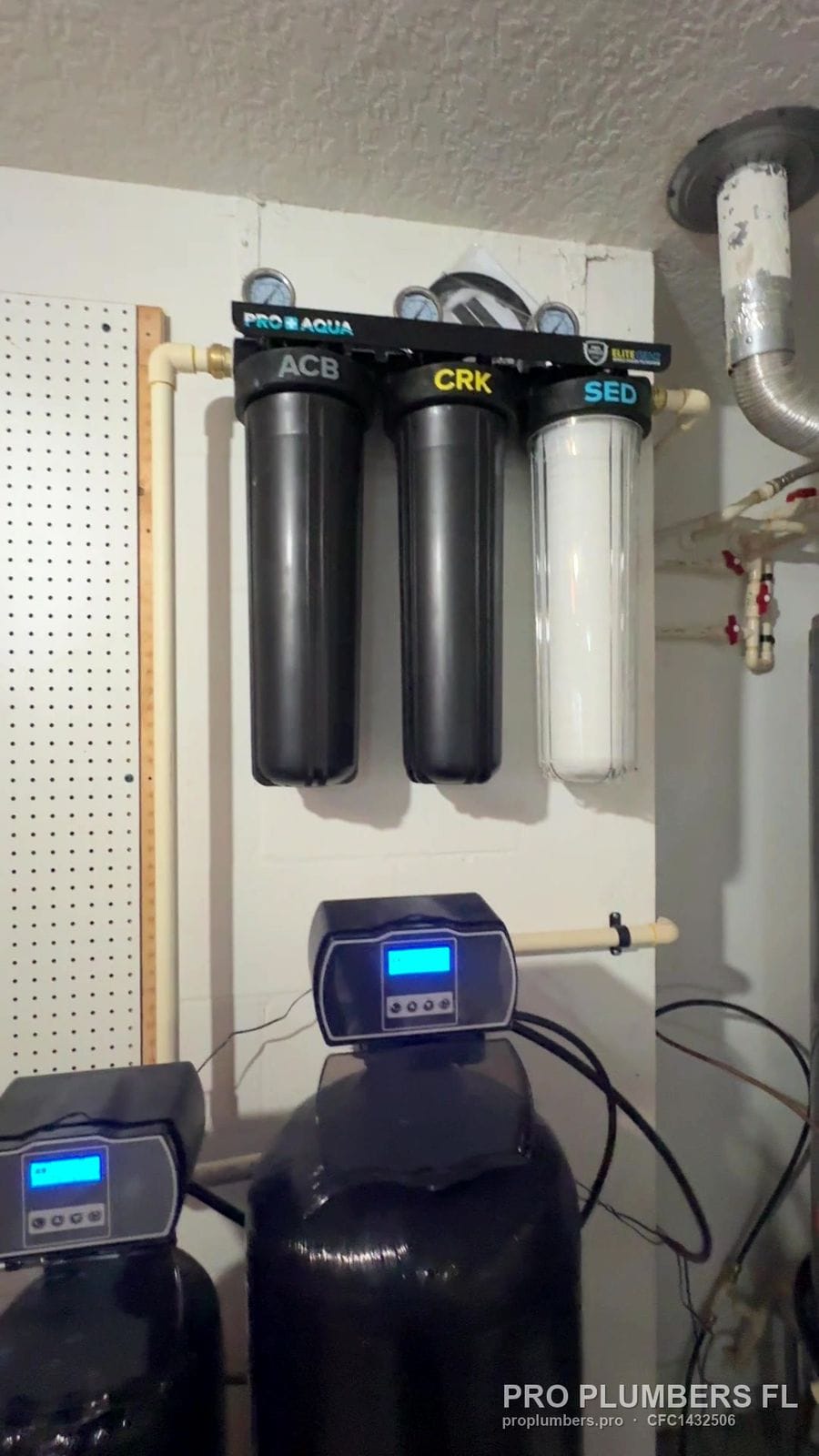Three-stage whole-house filter above a softener with digital control head in a garage in Tampa, Florida by PRO PLUMBERS FL, LLC (licence CFC1432506)
