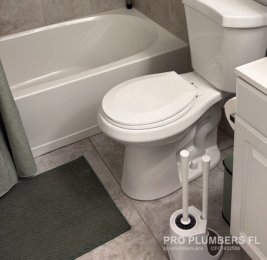 New two-piece toilet beside a bathtub on grey tile in Clearwater, Florida by PRO PLUMBERS FL, LLC (licence CFC1432506)