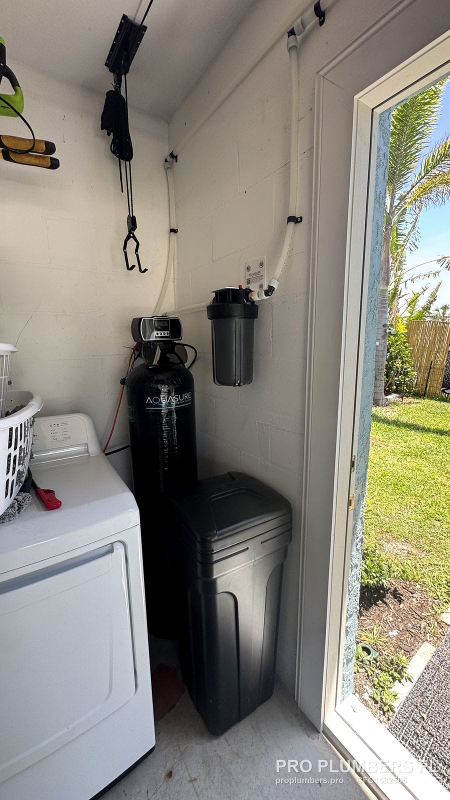 AQUASURE water softener, brine tank and prefilter installed in a utility closet next to a dryer in South Pasadena, Florida by PRO PLUMBERS FL, LLC (licence CFC1432506)