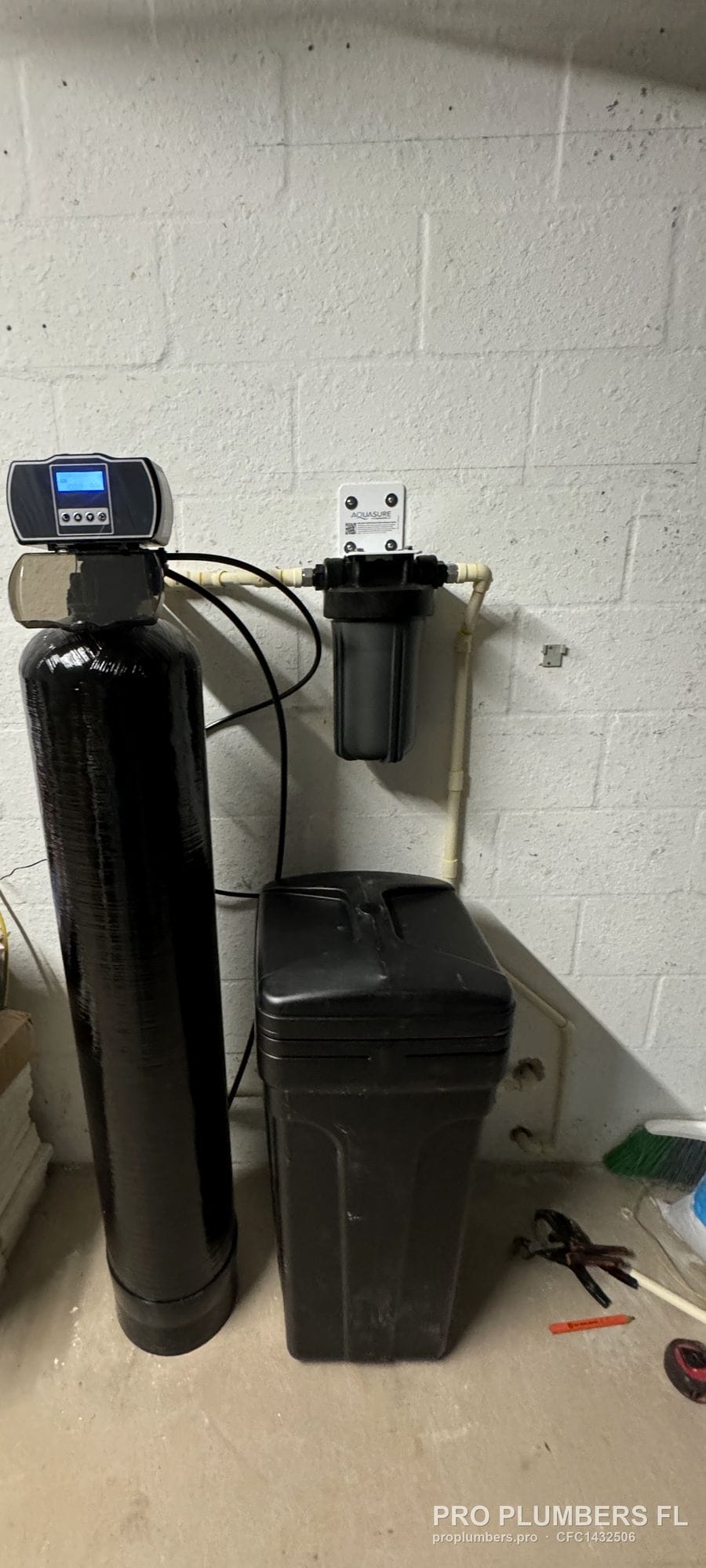 Water softener in service with lit control display next to its brine tank and prefilter housing in Venice, Florida by PRO PLUMBERS FL, LLC (licence CFC1432506)