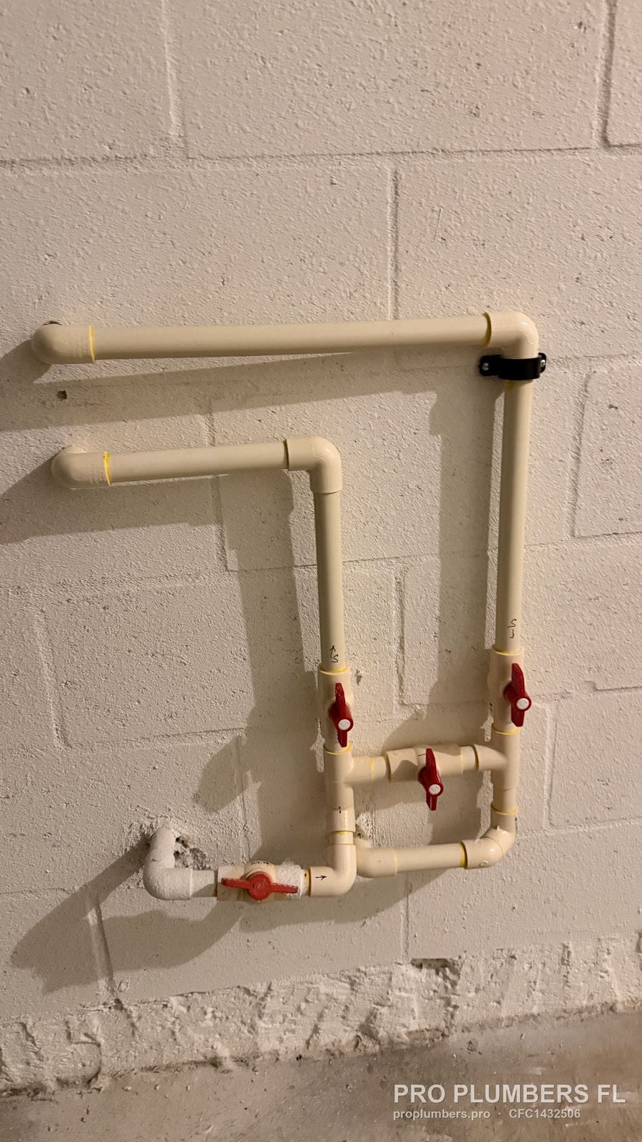 CPVC bypass manifold with four red-handle ball valves prepared on a block wall before the softener is set in Wesley Chapel, Florida by PRO PLUMBERS FL, LLC (licence CFC1432506)