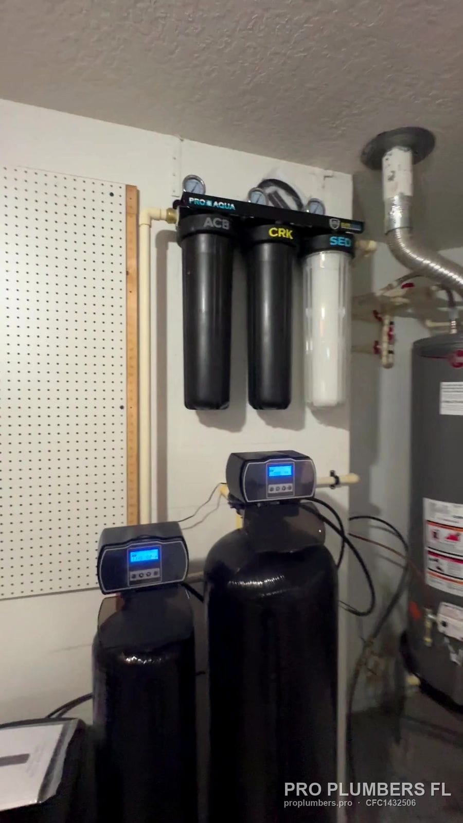 Whole-house filtration and twin softener tanks next to a gas water heater in Tampa, Florida by PRO PLUMBERS FL, LLC (licence CFC1432506)