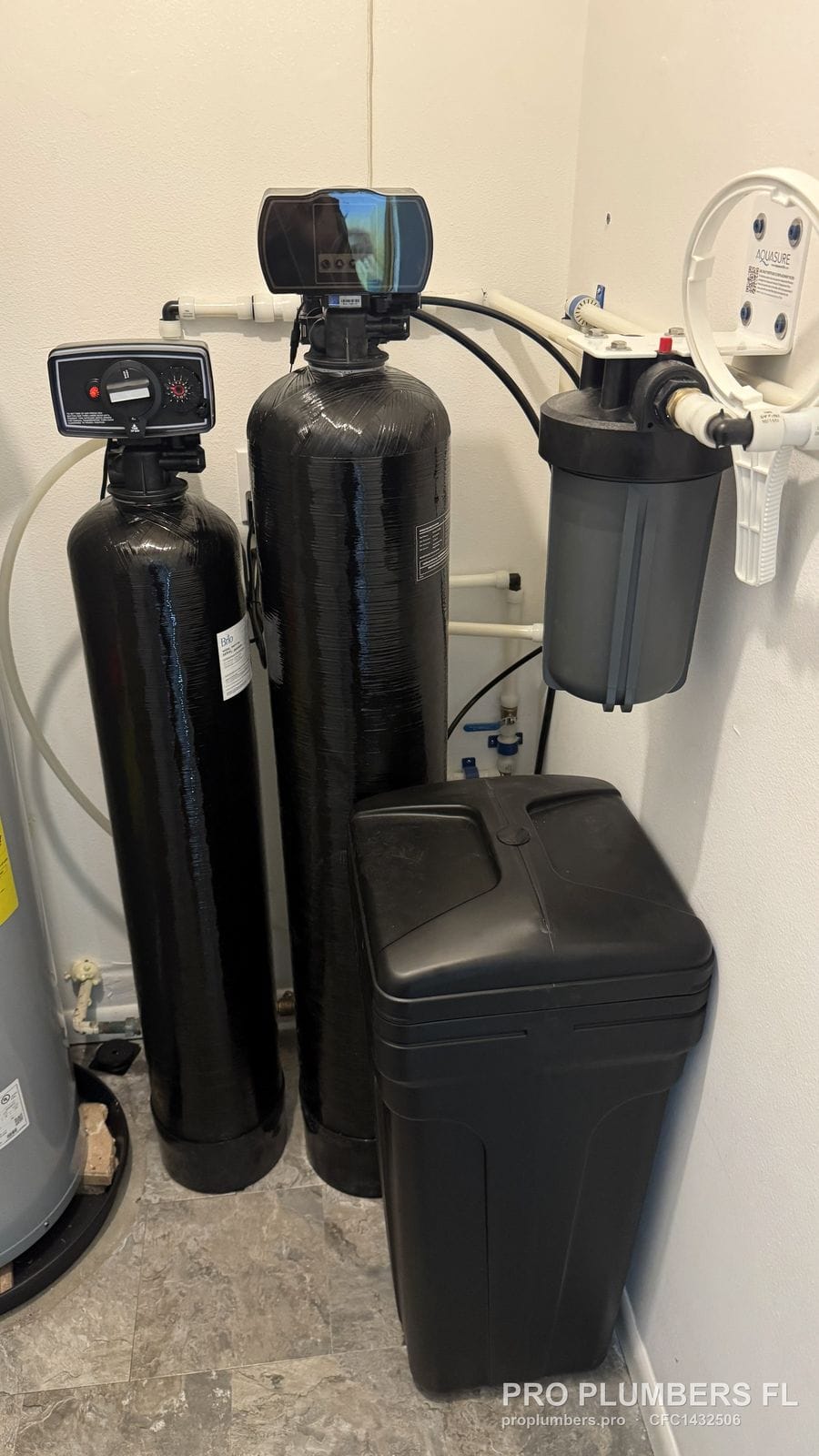 Filter tank and water softener with brine tank and wall-mounted prefilter in a utility closet in Belleair, Florida by PRO PLUMBERS FL, LLC (licence CFC1432506)