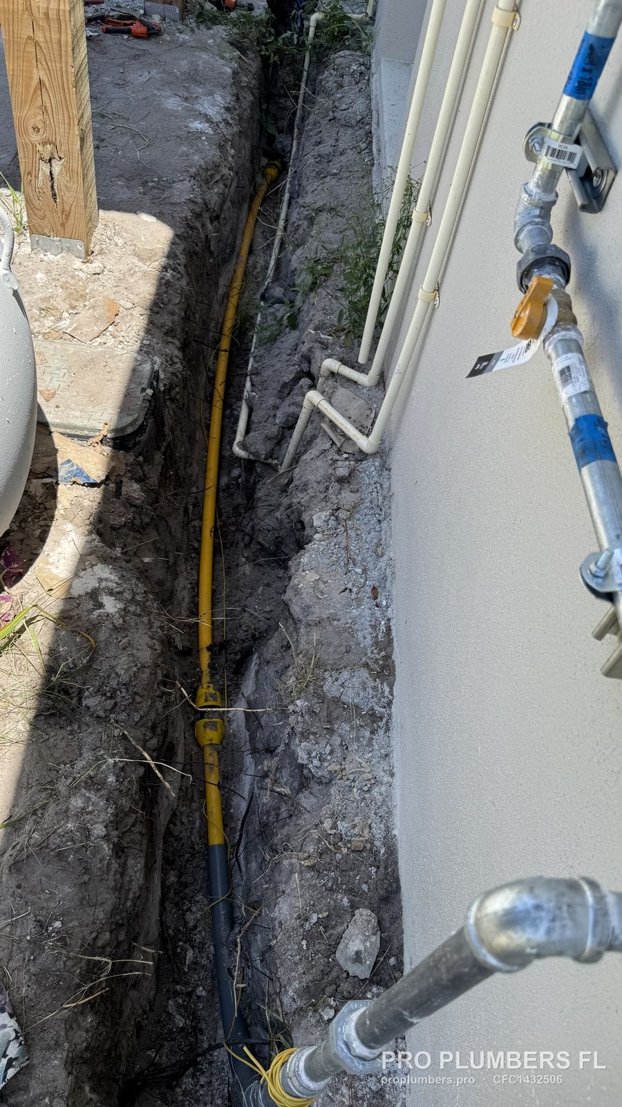 Yellow polyethylene gas line with tracer wire in a trench along a house in St Petersburg, Florida by PRO PLUMBERS FL, LLC (licence CFC1432506)
